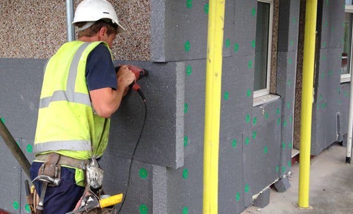 Operaio edile specializzato durante la posa dei pannelli isolanti per il cappotto termico